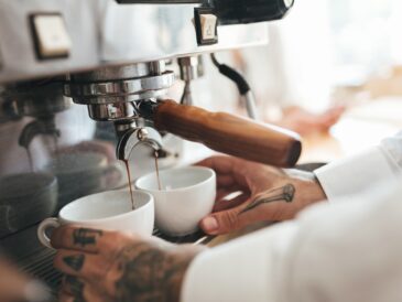 Close up barista hands making coffee by coffee machine in restaurant