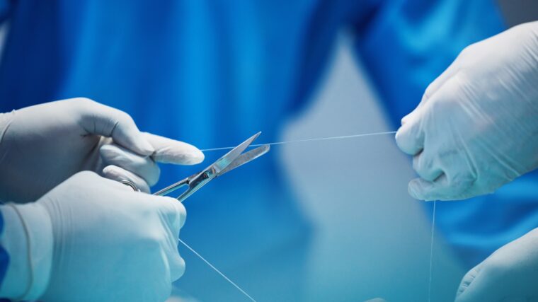 Surgery, hands and doctor cut thread, stitching patient and surgical procedure with health insuranc